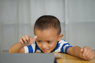 A boy watches a lesson on a portable computer.