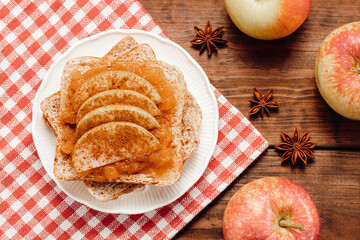 Toast  with apple jam with sliced apples topped with cinnamon, spices, wooden background. Autumn concept