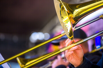 close-up of the hands of a  musician holding a gold-colored pump-action trumpet