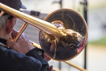 close-up of the hands of a  musician holding a gold-colored pump-action trumpet