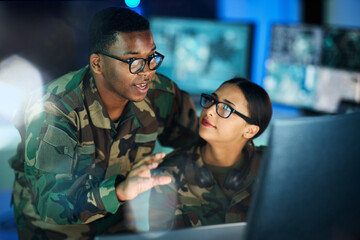 Fototapeta premium Night training, army and people with a computer for communication, planning strategy or surveillance. Cyber security, data center and a black man talking to a woman about monitor in a military room