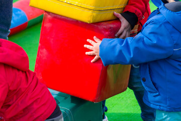 Children on the playground with green artificial turf playing large multi-colored cubes with the...