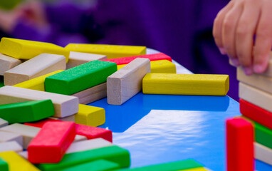 close-up of a child's hand playing wood blocks stack game	