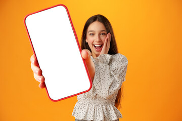 Teen girl showing smartphone screen with copy space over yellow background