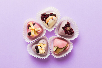 chocolate sweets in the form of a heart with fruits and nuts on a colored background. top view with space for text, holiday concept