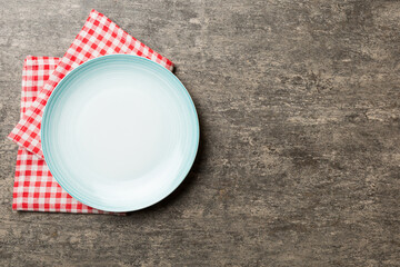 Top view on colored background empty round blue plate on tablecloth for food. Empty dish on napkin with space for your design