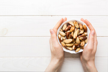 Woman hands holding a wooden bowl with brazil or bertholletia nuts. Healthy food and snack. Vegetarian snacks of different nuts