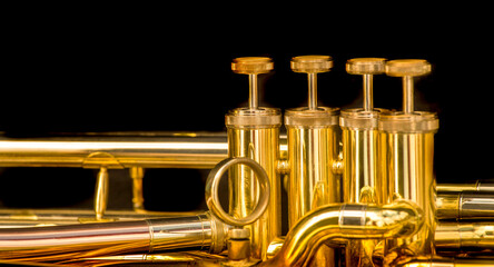 close-up of t a gold-colored pump-action trumpet on a black background