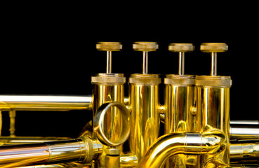 close-up of t a gold-colored pump-action trumpet on a black background