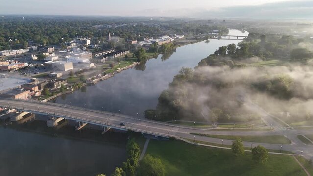 A high angle aerial establishing shot view of the Saginaw River with the town in the distance. The Frank N. Andersen Celebration Park below.  	