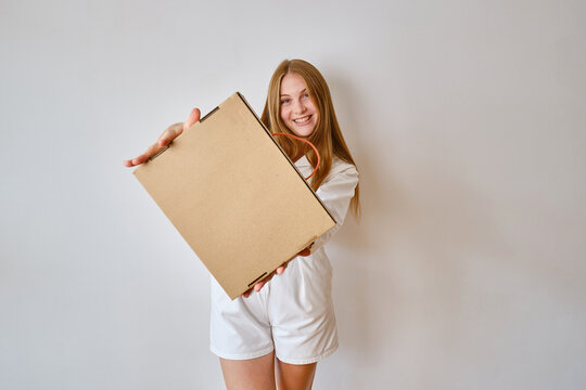 Happy woman holding in hand paper box. Young girl with new package. Postal service, delivery. Craft paper. Gift box, present. Box closeup. Blank packing, empty space. Carton case 