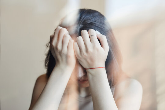 Distorted portrait of young woman struggling with mental health issues and covering face