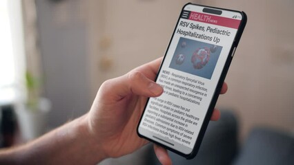 Reading news article on phone about increase in RSV infections.