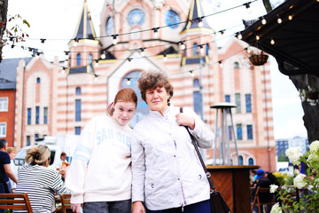 Grandmother and granddaughter walk through an old European city.
