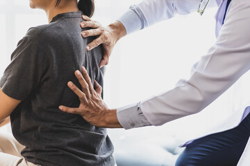 Doctor examining woman back pain in examination room. Doctor practicing back and shoulder...