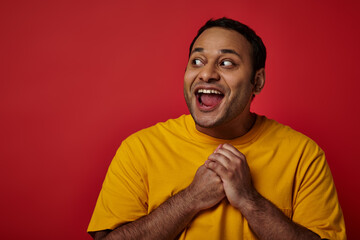 astonished indian man with wide eyes open looking away on red background in studio, surprise concept