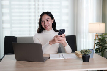 Cheerful young Chinese business woman talking on phone working in modern office.