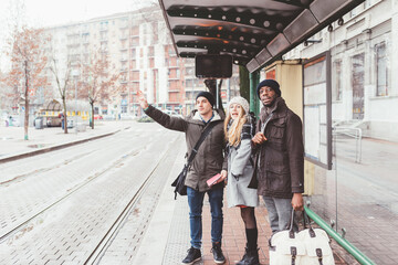 three people young multiethnic friends asking taxi