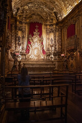 Fototapeta na wymiar Rio de Janeiro, Brazil: woman from behind praying in the Chapel of the Blessed Sacrament in the Abbey of Our Lady of Montserrat (Monastery of St. Benedict), Benedictine abbey founded by monks in 1590 