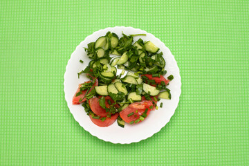 salad of tomatoes and cucumbers with herbs on a white plate