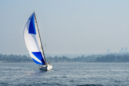 Sailboat sailing spinnaker on smoke filled hazy sky day north of Seattle in Puget Sound.