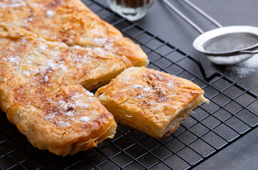 Greek pie called Bougatsa with cheese slightly blurred cross section and selective focus on powdered sugar and cinnamon