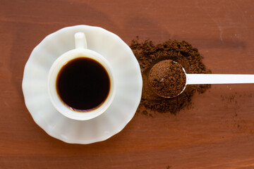 Vista superior taza de café y una cuchara con café molido sobre una mesa de madera 