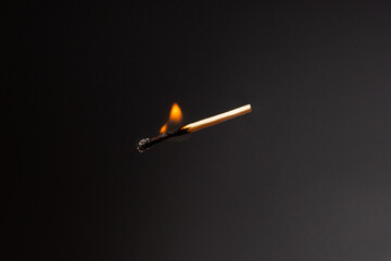 Lit falling match on a black background.