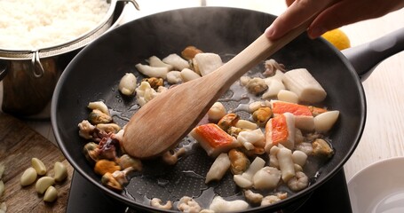 Cooking seafood dishes. Seafood cocktail with shrimp, octopus and mussels are fried in a pan, stirring with a spatula. A series of photos to visualize the recipe. Food preparation.