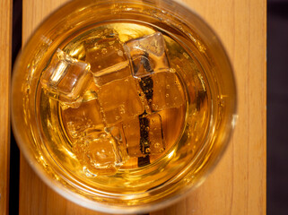 Glass of whiskey with ice on a wooden table. Whiskey with ice close-up