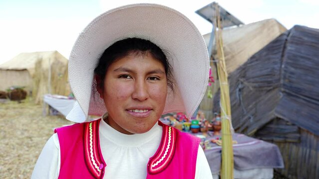 Portrait of an indigenous Peruvian young woman standing at floating islands of Uros, Lake Titicaca, Puno, Peru. Aymara indigenous people.