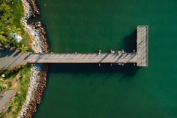 Top view of wooden pier and quiet sea with sun light, aerial view