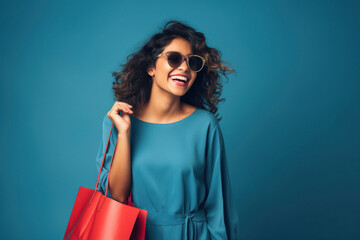 Young woman wearing sunglasses and holding shopping bags.