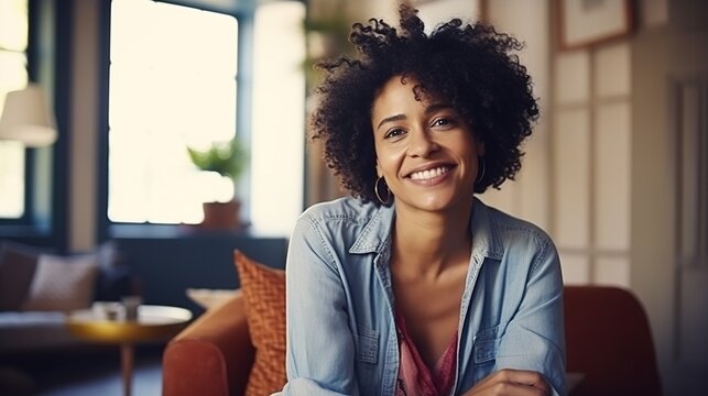 Happy woman with a beautiful smile sits comfortably at a desk or table indoors, showcasing a casual and stylish lifestyle