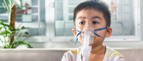 Asian Child using nebulizer mask equipment alone have smoke, Kid boy making makes inhalation...