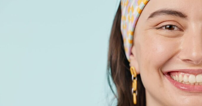 Half face, space and smile with a woman closeup on a blue background for marketing in studio. Portrait, mockup and a happy young person on a blank or empty banner for wellness advertising in studio
