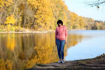 Girl in a yellow autumn park. Beautiful young woman walks along the path of the autumn park.