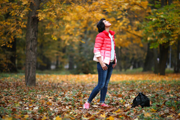 Girl in a yellow autumn park. Beautiful young woman walks along the path of the autumn park.