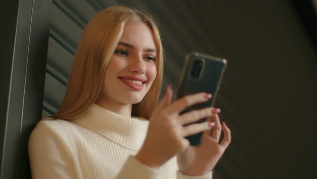 Smiling Caucasian woman student businesswoman browsing internet texting messages on mobile phone happy girl using smartphone download video surfing social networks young gen z and modern technology