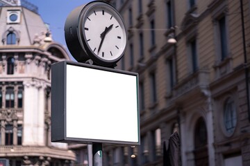 Blank white poster under a clock in Milan.