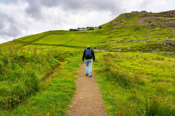 Fototapeta premium Man hiking down a path up the mountain on the Isle of Skye, Scotland.