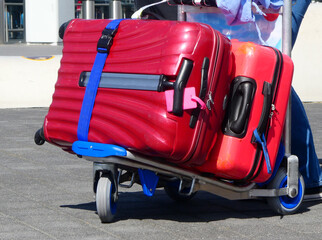 Fototapeta na wymiar A luggage trolley with two red suitcases