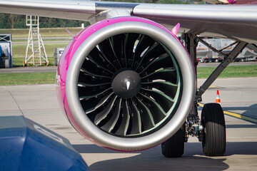 Detailed view of commercial aircraft engine, landing gear and wing. Boarding airplane on airport runway.