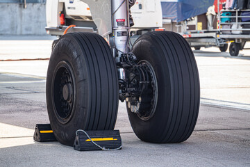 Detailed view of commercial aircraft main landing gear. Airplane wheels with tires on airport runway.