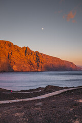 Sunlitted rocks Los Gigantes during sunset at the atlantic ocean with wooden path in a foreground