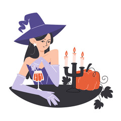 Young witch in a hat drinks an alcoholic cocktail by candlelight
