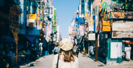 Asian girl standing out from the crowd at a city street in Japan. - obrazy, fototapety, plakaty