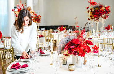 Red gold color flower decor for Chinese New Year celebration. Girl woman florist, decorator, organizer of events, parties, wedding planner making floral arrangement, festive bouquet, table decoration