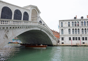 Fototapeta na wymiar Rialto bridge with few boats and without people during the lockdown inflicted by the pandemic
