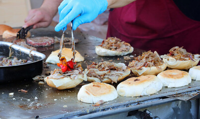 cook in the street food stall preparing a stuffed sandwich with meat and vegetables